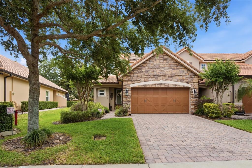 A tan stucco house with a stone facade, a two-car garage, and a paved driveway — 10321 BELFRY CIRCLE, ORLANDO, FL