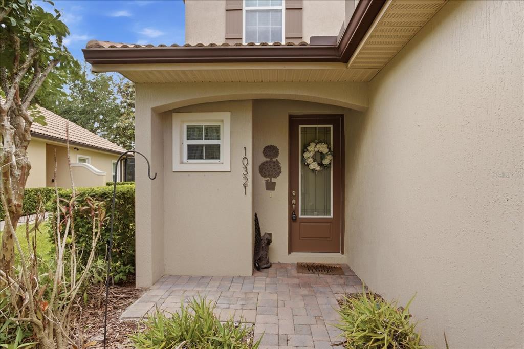 The exterior entrance features a brown front door, a small window, and a paved walkway — 10321 BELFRY CIRCLE, ORLANDO, FL