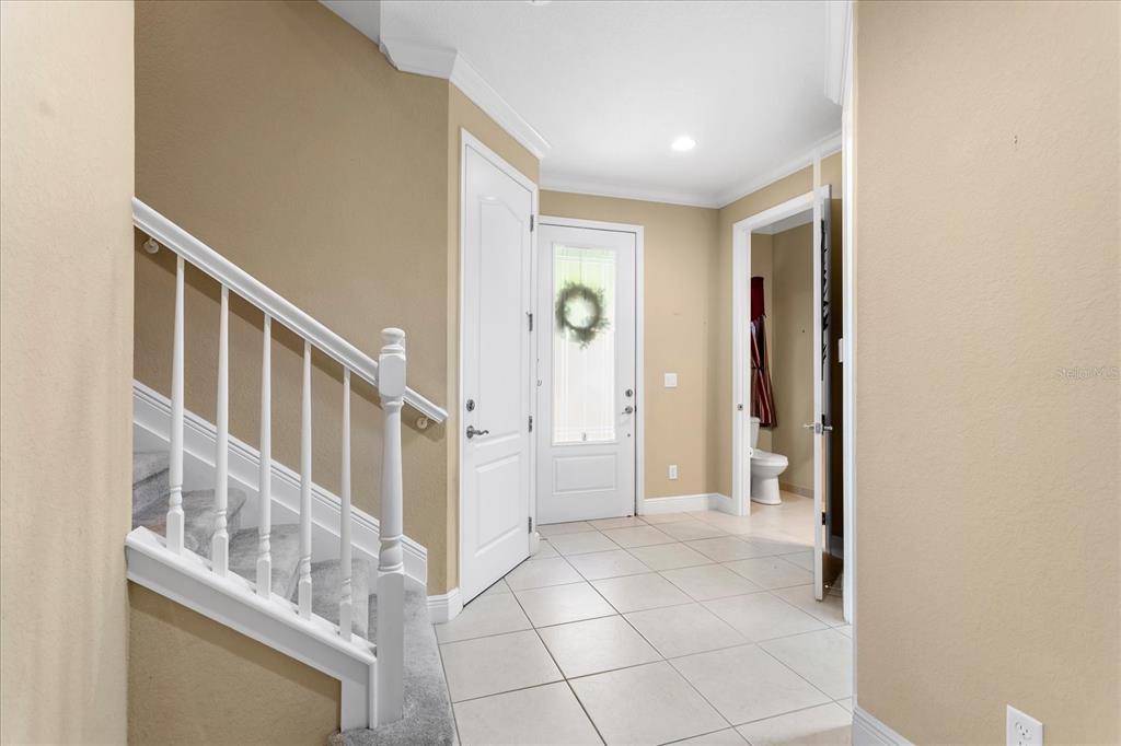 An entryway features a staircase with white railings, tile flooring, and a front door — 10321 BELFRY CIRCLE, ORLANDO, FL
