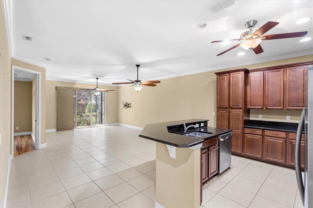 An open-concept kitchen and living area features tile flooring, dark wood cabinetry, and ceiling fans — 10321 BELFRY CIRCLE, ORLANDO, FL
