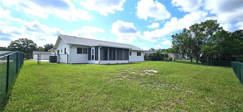The exterior of a white house features a screened-in porch and a fenced backyard — 10854 SW 78TH COURT, OCALA, FL
