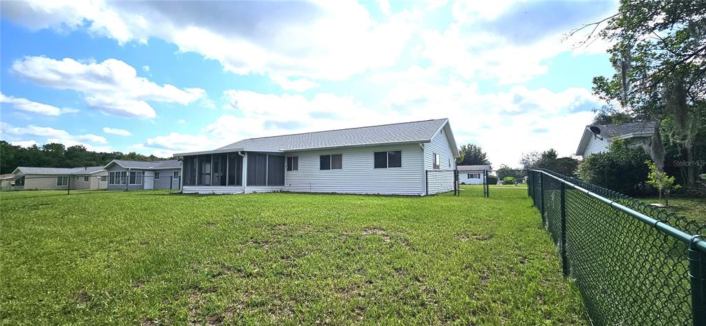 The exterior of a white house with a screened-in porch and a chain-link fence — 10854 SW 78TH COURT, OCALA, FL