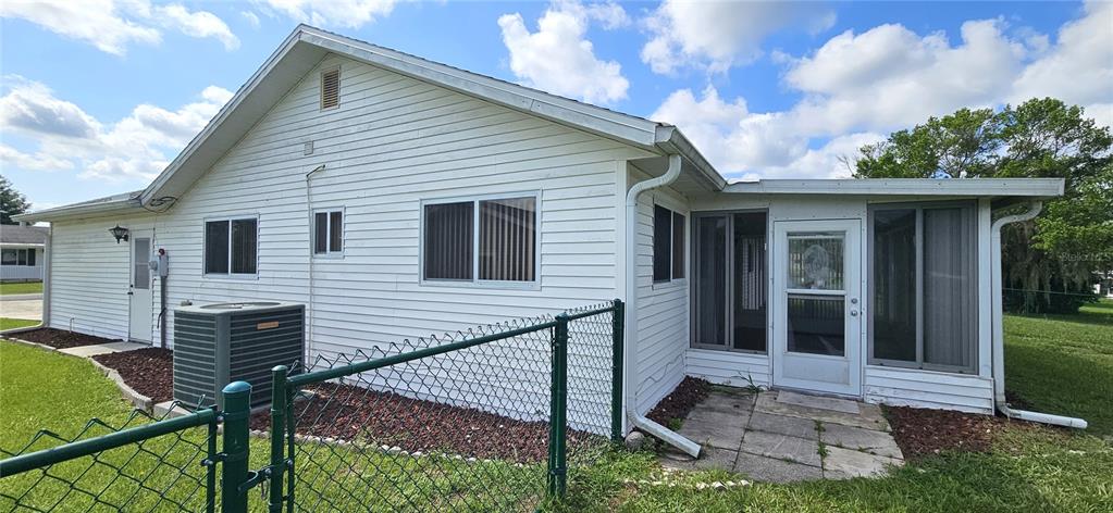 The exterior of a white-sided house features a screened-in porch and a chain-link fence — 10854 SW 78TH COURT, OCALA, FL