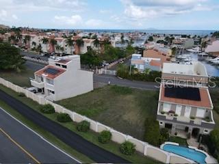 An aerial view shows a vacant residential lot situated between two houses near the coast — MARINA VIEW 5 UNIT 5, HUMACAO, PR