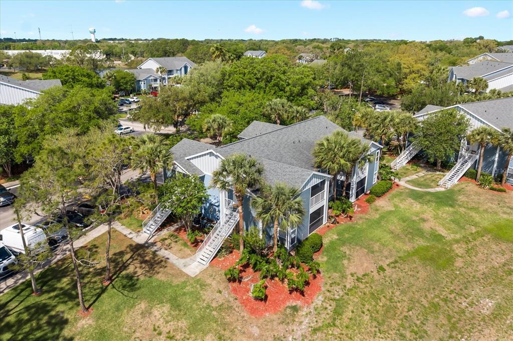 An aerial view shows a multi-story apartment building surrounded by trees and a parking lot — 2501 GRASSY POINT DRIVE UNIT 103, LAKE MARY, FL
