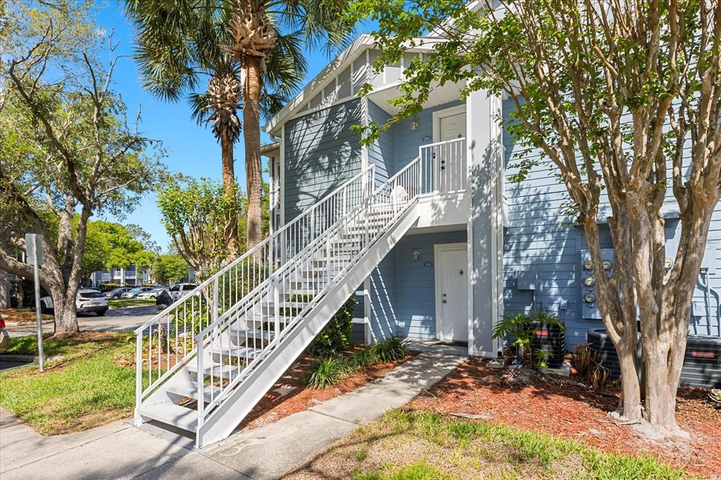 An exterior view of a two-story blue apartment building with an outdoor metal staircase — 2501 GRASSY POINT DRIVE UNIT 103, LAKE MARY, FL