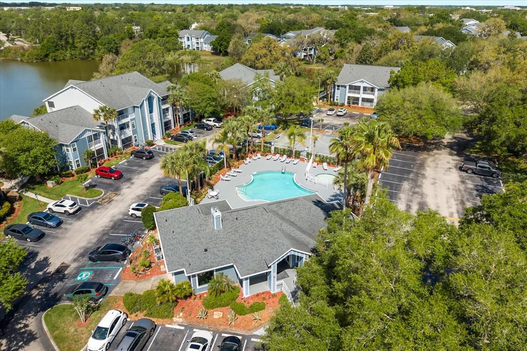 An aerial view of an apartment complex featuring a swimming pool, parking lot, and buildings — 2501 GRASSY POINT DRIVE UNIT 103, LAKE MARY, FL