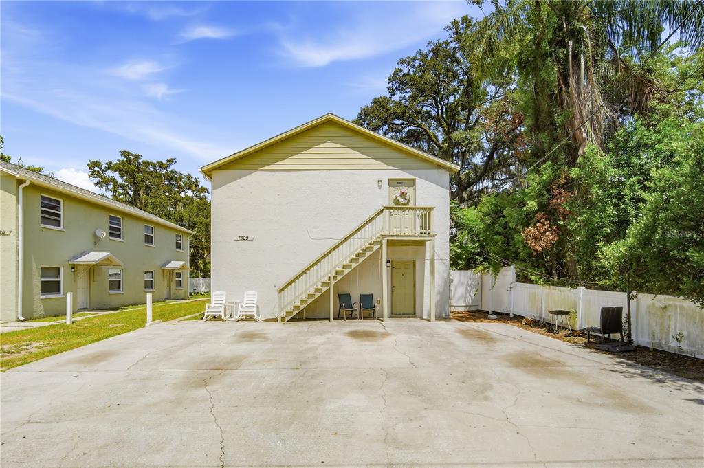 A two-story apartment building with an exterior staircase and a concrete parking area — 7309 N HUTTON PLACE UNIT D, TAMPA, FL