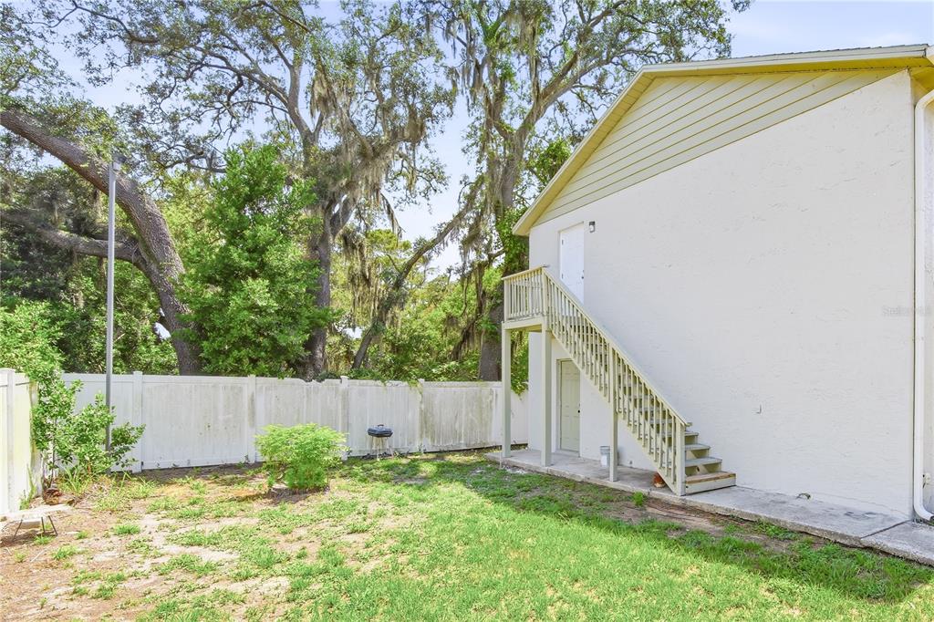 A two-story building exterior features a wooden staircase leading to an upper-level door — 7309 N HUTTON PLACE UNIT D, TAMPA, FL