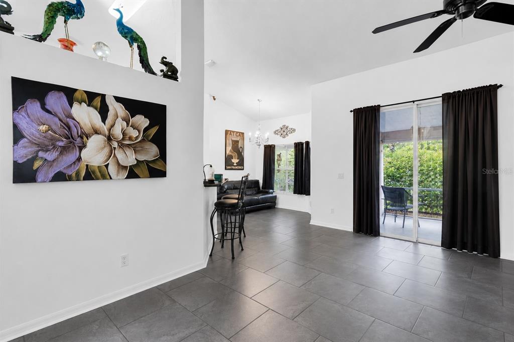 A living area features gray tile flooring, a breakfast bar, and sliding glass patio doors — 13270 DRYSDALE STREET, SPRING HILL, FL