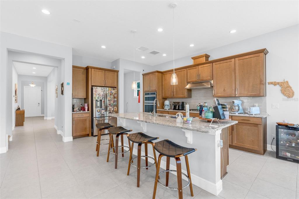 A covered patio features a stone floor, outdoor kitchen with bar seating, and dining area — 15161 CANOE PLACE, WINTER GARDEN, FL