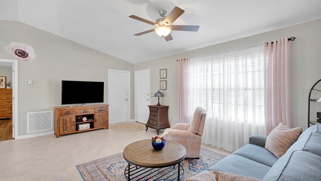 A living room features tile floors, a ceiling fan, a television, and a sofa — 1080 HAMMACHER AVENUE SW, PALM BAY, FL