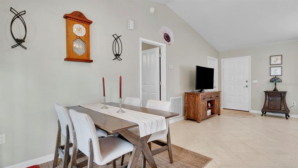 A dining area features a wooden table with four chairs, a wall clock, and tile flooring — 1080 HAMMACHER AVENUE SW, PALM BAY, FL
