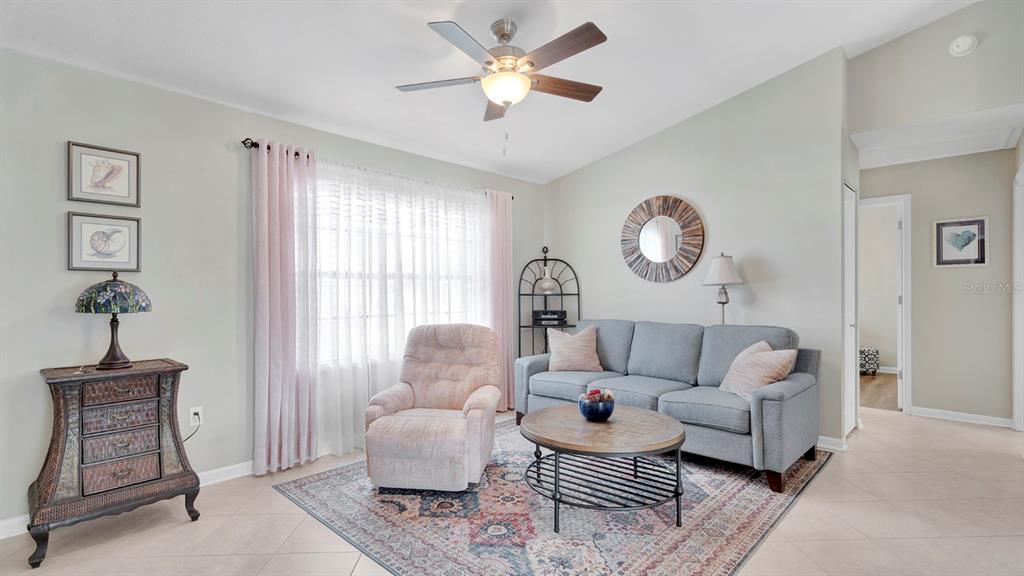 A living room features a gray sofa, a pink recliner, and a round coffee table — 1080 HAMMACHER AVENUE SW, PALM BAY, FL