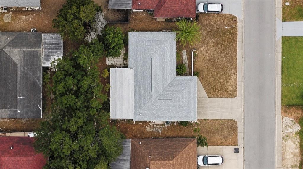 An aerial view shows a house with a gray roof surrounded by trees and lawns — 8923 CANDLEWICK LANE, PORT RICHEY, FL