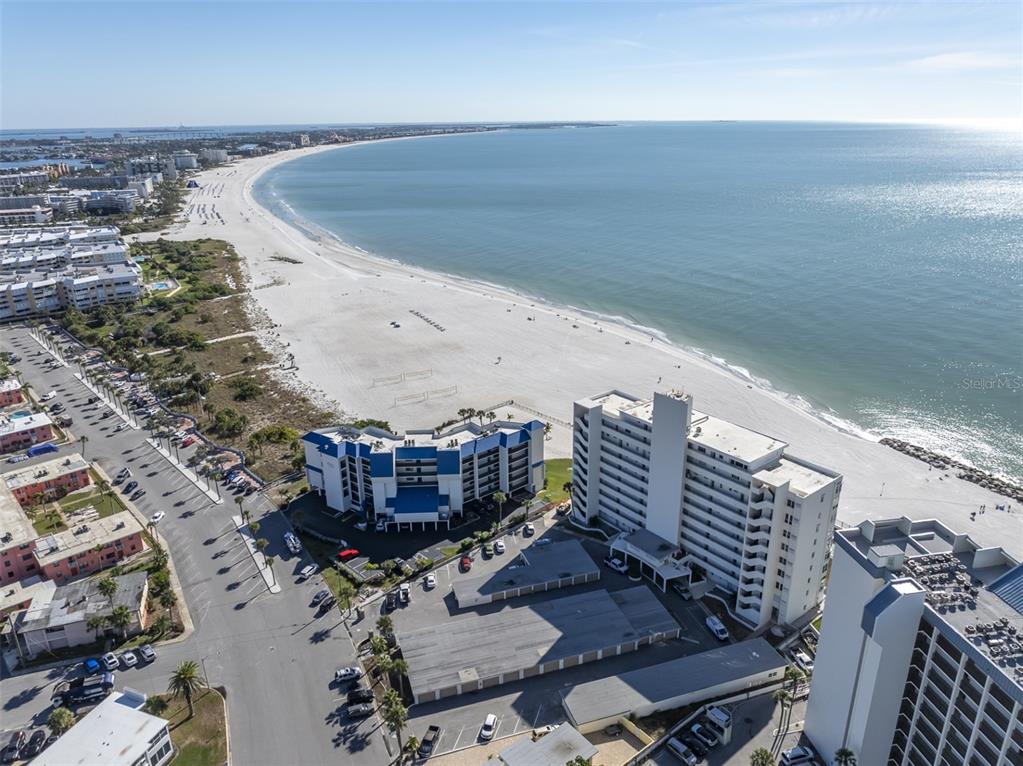 An aerial view shows a coastal beach with high-rise buildings and a parking lot — 680 71ST AVENUE UNIT 14, ST PETE BEACH, FL