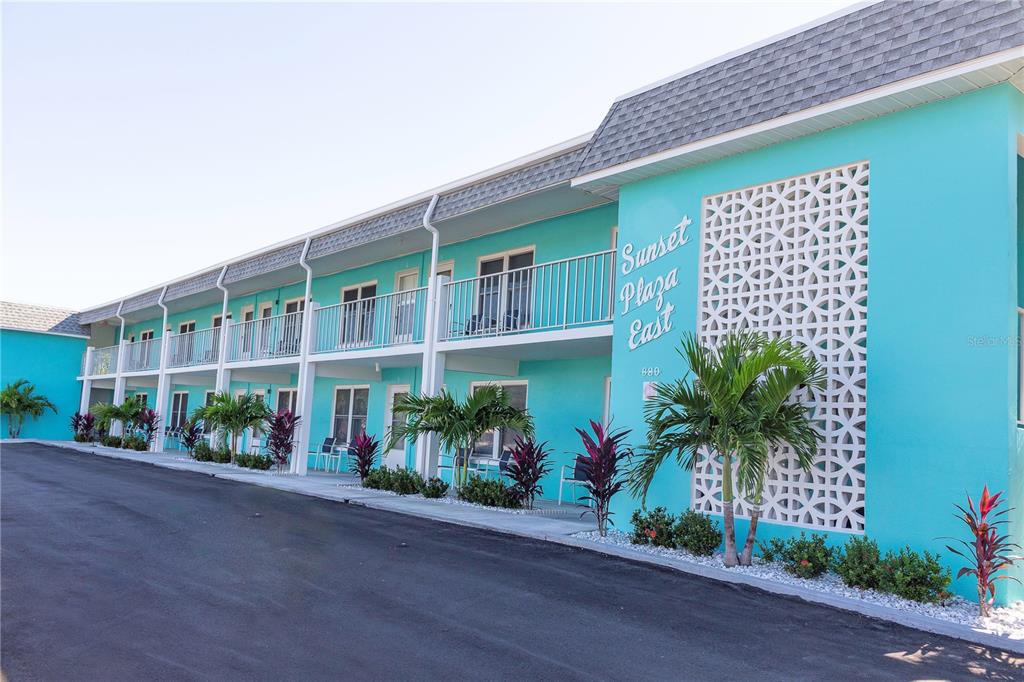 A two-story turquoise motel building features a decorative screen wall and a paved parking lot — 680 71ST AVENUE UNIT 14, ST PETE BEACH, FL