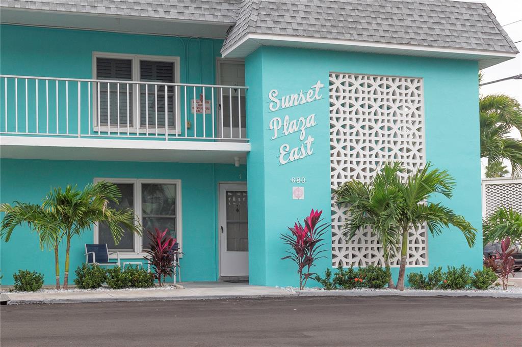The exterior of a teal two-story building features a white balcony and decorative lattice screen — 680 71ST AVENUE UNIT 14, ST PETE BEACH, FL