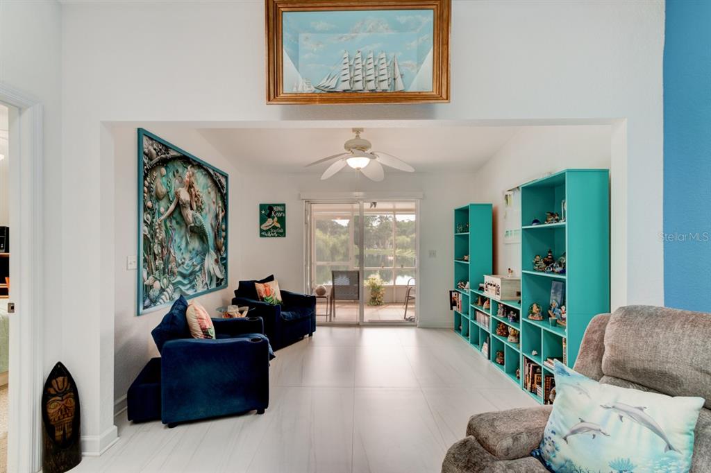 A living room features white tile floors, blue armchairs, teal shelving, and a large mermaid mural — 2246 HAWKS COVE CIRCLE, NEW SMYRNA BEACH, FL