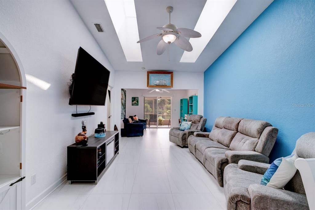 A living room features a blue accent wall, gray reclining furniture, and two skylights — 2246 HAWKS COVE CIRCLE, NEW SMYRNA BEACH, FL