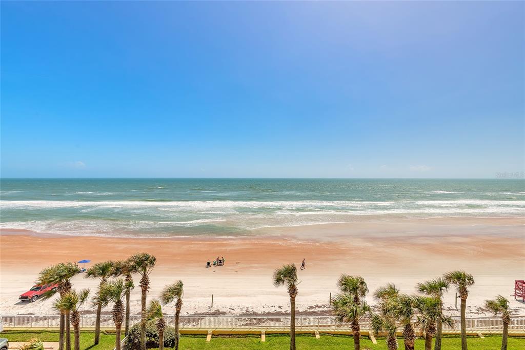 A high-angle view of a sandy beach with palm trees and the ocean beyond — 2300 N ATLANTIC AVENUE UNIT 301, DAYTONA BEACH, FL