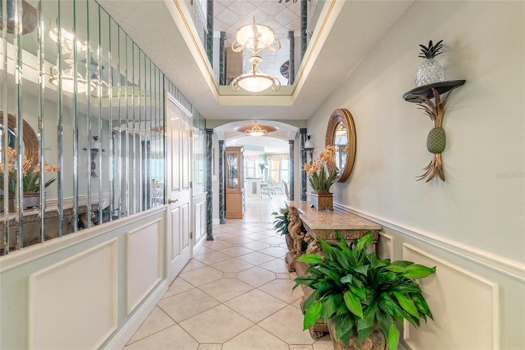 A tiled hallway features mirrored walls, a tray ceiling with chandeliers, and a console table — 2300 N ATLANTIC AVENUE UNIT 301, DAYTONA BEACH, FL