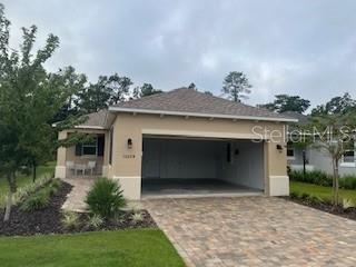A tan single-story house with a two-car garage and a paved driveway — 10274 SW 99TH LANE, OCALA, FL