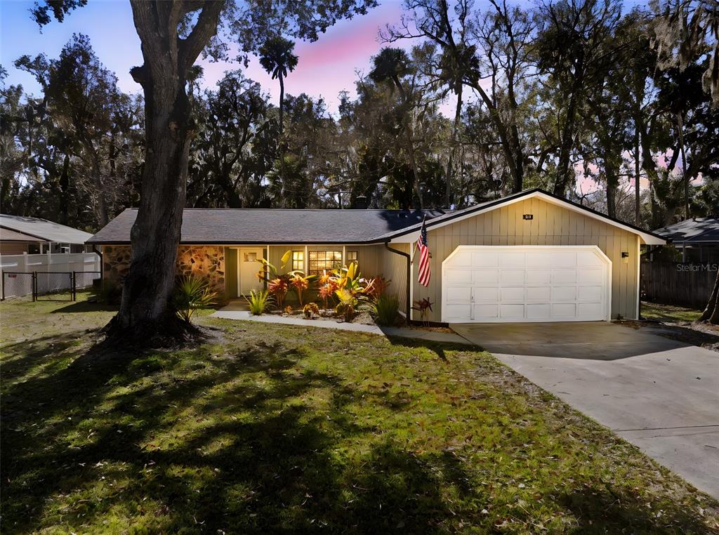 A single-story house with a two-car garage, stone accents, and a front yard with trees — 813 SUGAR HOUSE DRIVE, PORT ORANGE, FL