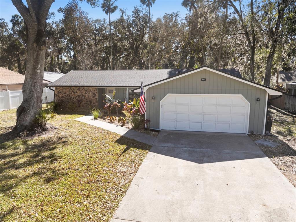 A single-story house with a stone facade, green siding, and a two-car garage — 813 SUGAR HOUSE DRIVE, PORT ORANGE, FL