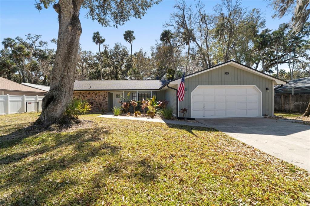 A single-story house with a stone facade, green siding, and a two-car garage — 813 SUGAR HOUSE DRIVE, PORT ORANGE, FL