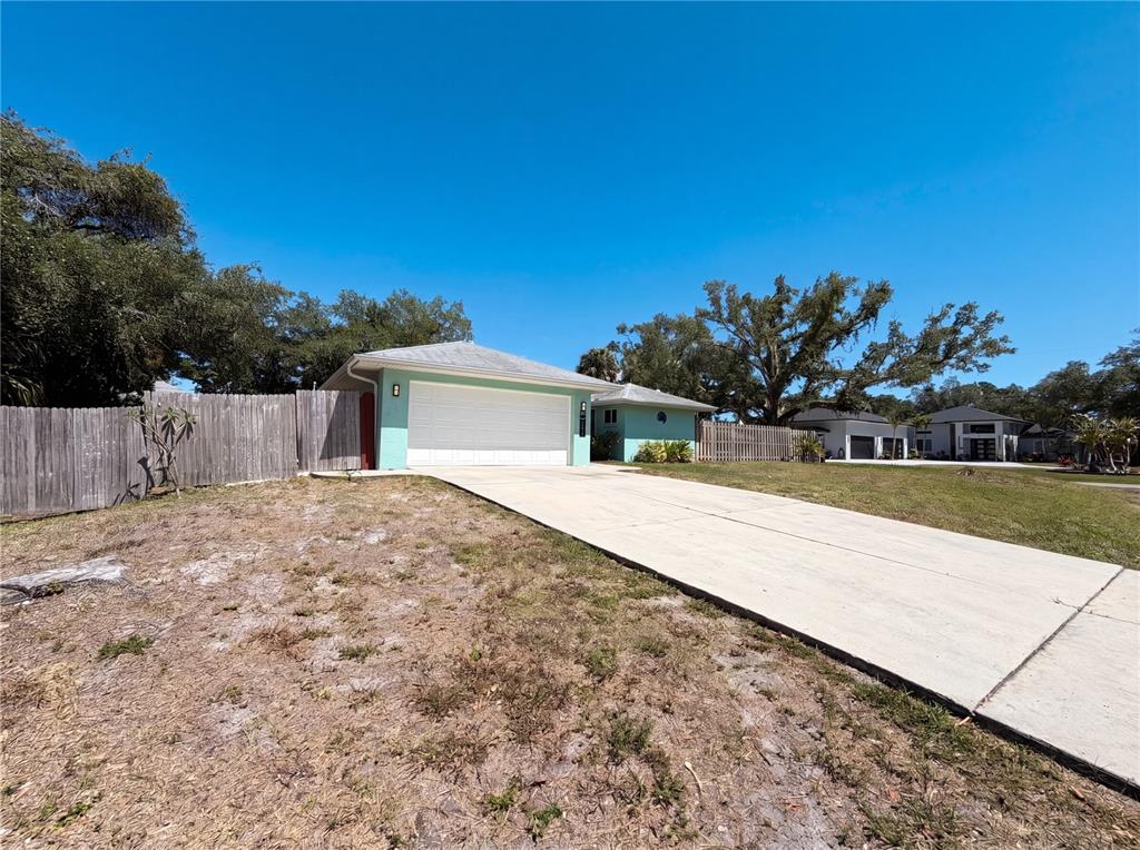 A light green house with a white garage door sits behind a concrete driveway — 212 WASHINGTON AVENUE, OSPREY, FL