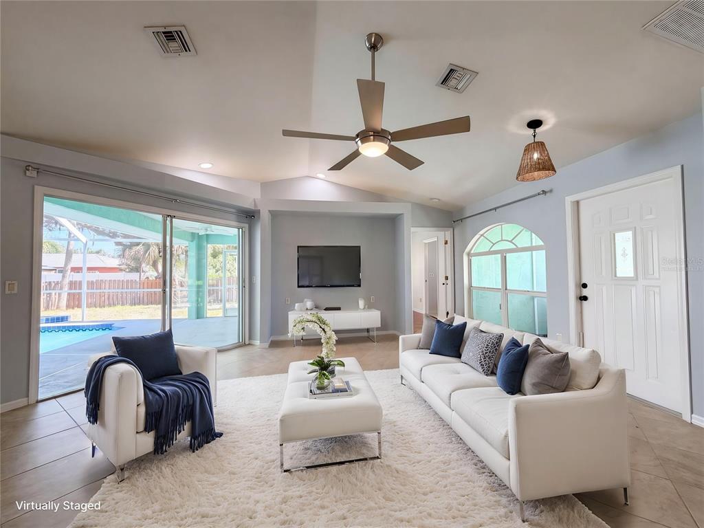 A living room features a white sofa, armchair, ottoman, ceiling fan, and sliding glass doors — 212 WASHINGTON AVENUE, OSPREY, FL
