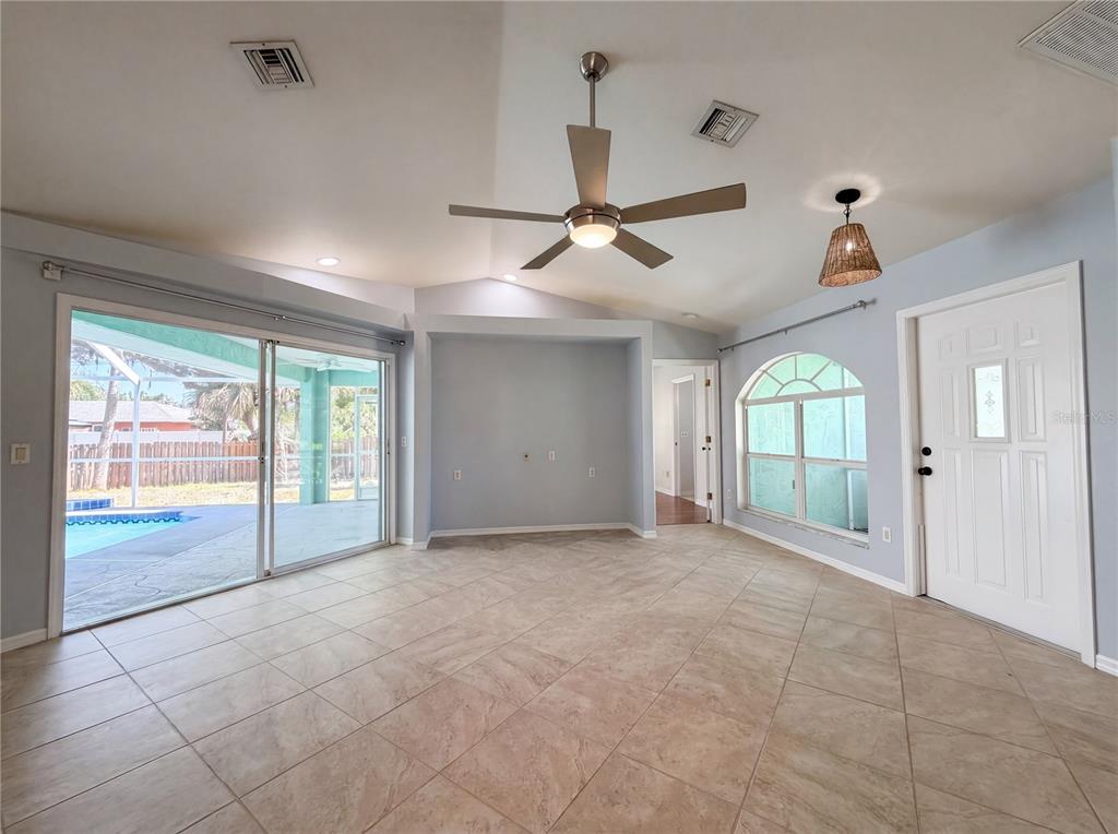 A living room with tile floors, a ceiling fan, sliding glass doors, and an arched window — 212 WASHINGTON AVENUE, OSPREY, FL