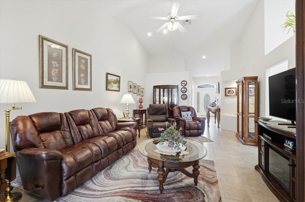 A living room features a brown leather sofa, matching recliners, and a glass coffee table — 6845 SHIMMERING DRIVE, LAKELAND, FL