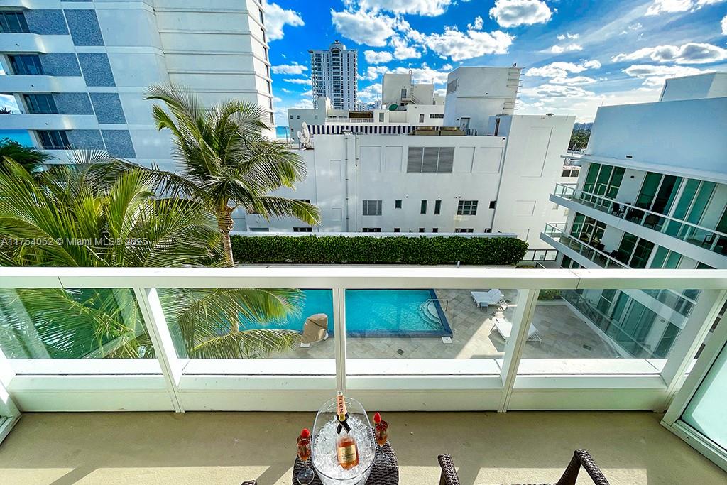 A balcony overlooks a swimming pool with a bottle of champagne in an ice bucket — 4391 Collins ave # 616, Miami Beach FL 33140, MIAMI BEACH, FL