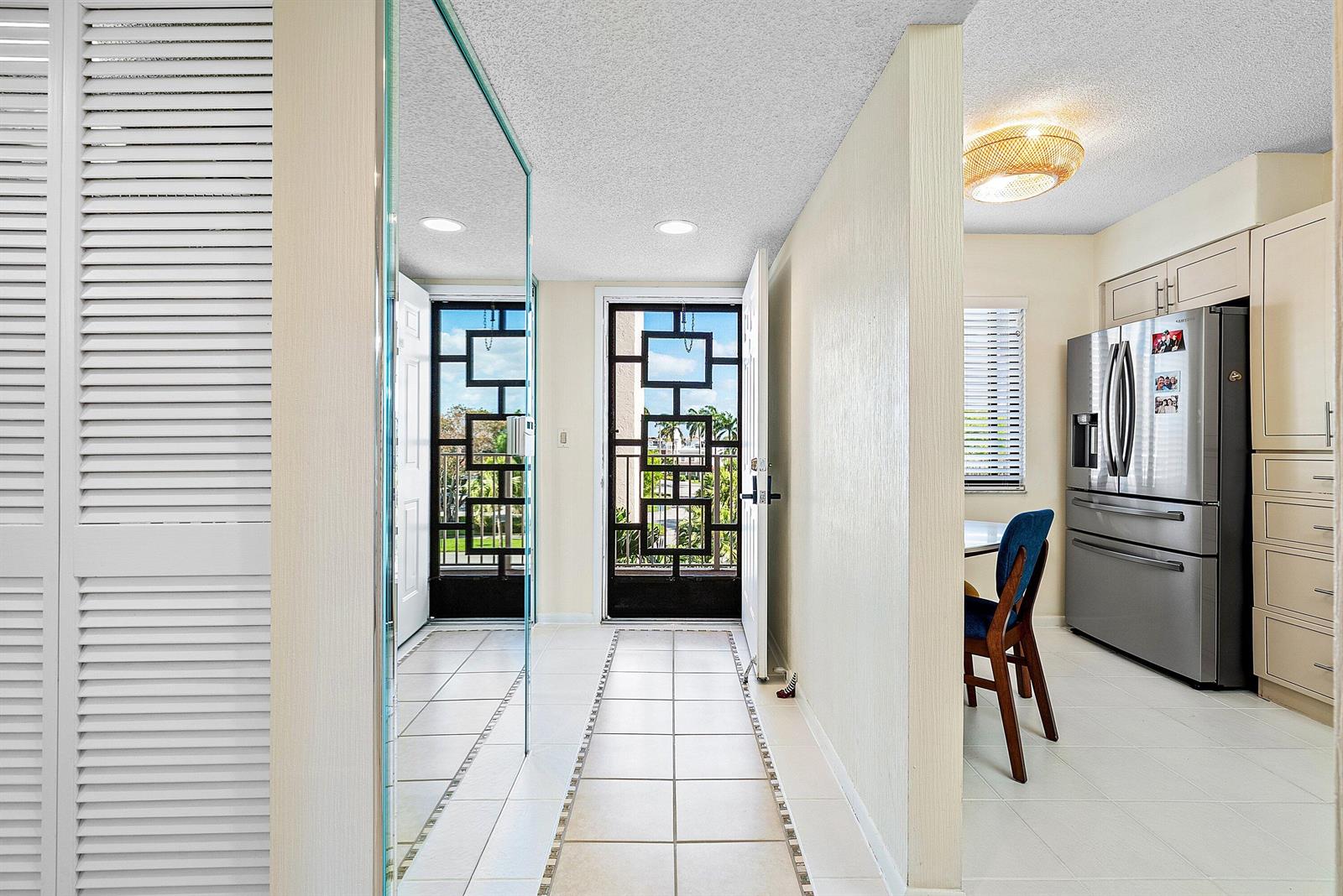 A tiled entryway leads to a doorway with a decorative metal screen and a kitchen — 6065 Pointe Regal Circle, Delray Beach FL 33484, DELRAY BEACH, FL