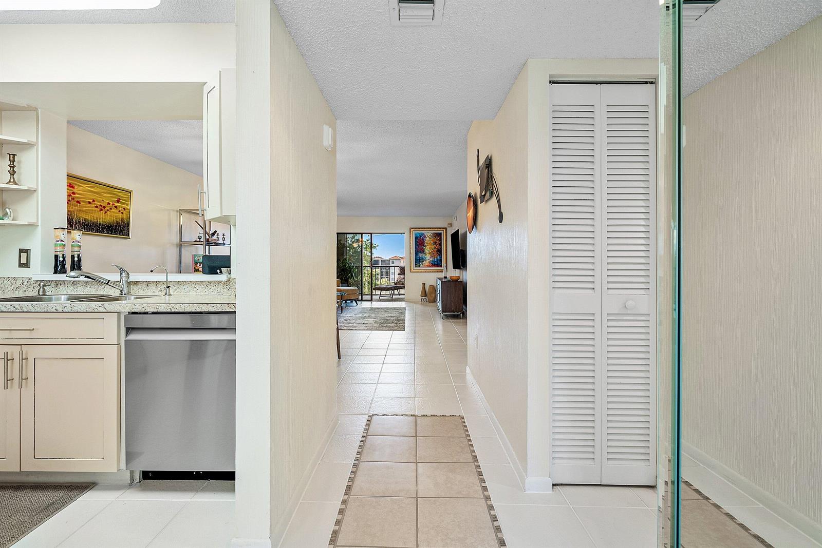 A hallway with tiled floors leads from a kitchen toward a living area with balcony — 6065 Pointe Regal Circle, Delray Beach FL 33484, DELRAY BEACH, FL