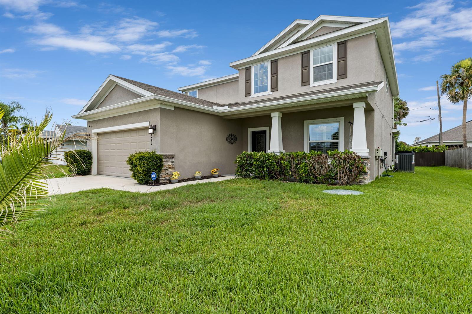 A two-story suburban house with a beige stucco exterior, a garage, and a front lawn — 2241 SW Abalon Circle, FL 34953, FL