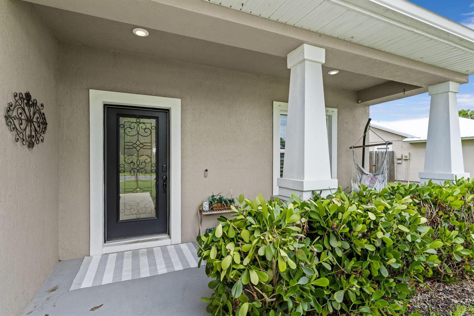 A covered front porch features a dark door with glass inlay and white columns — 2241 SW Abalon Circle, FL 34953, FL