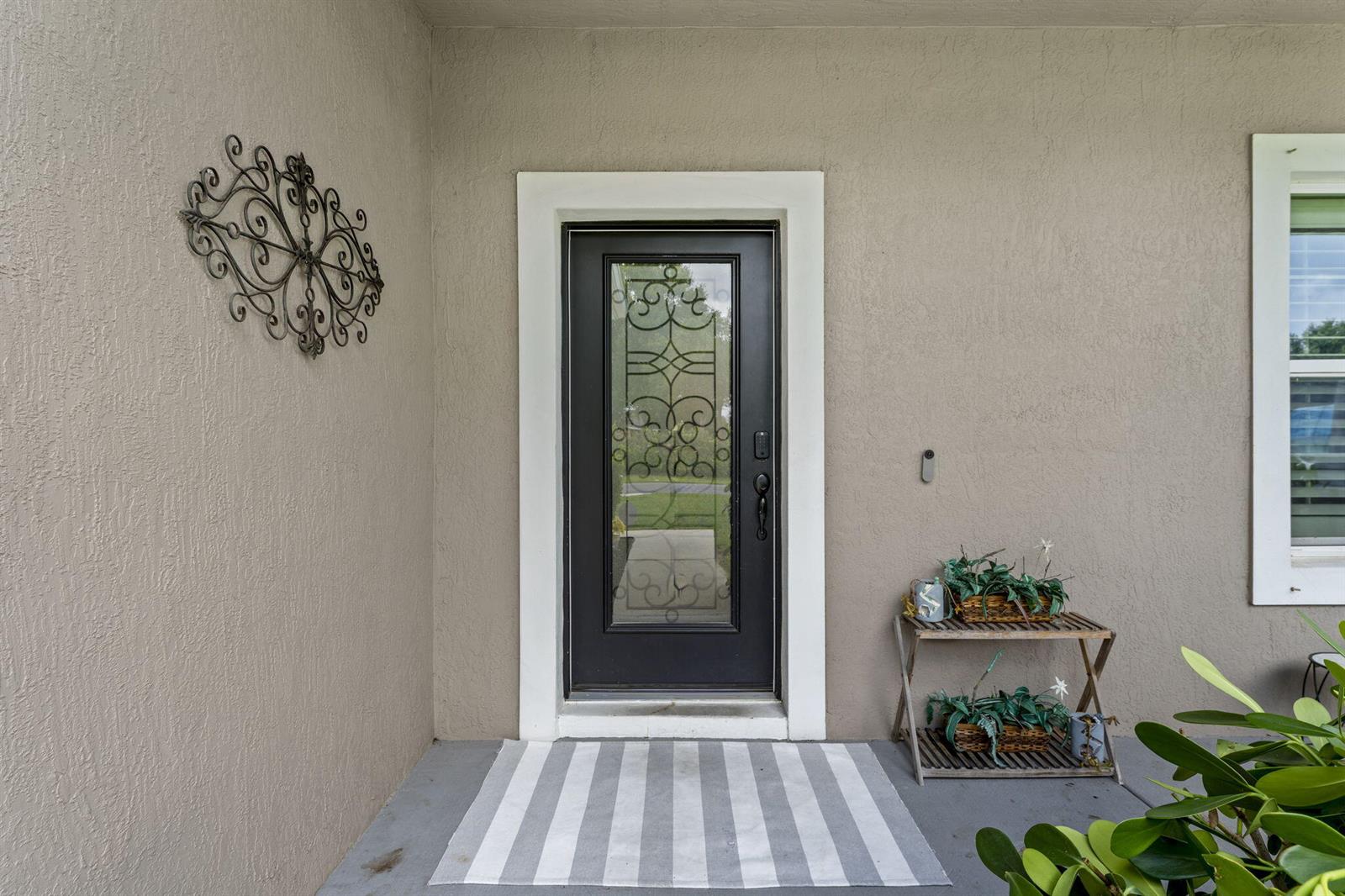 A dark front door with a glass insert sits on a porch with a rug — 2241 SW Abalon Circle, FL 34953, FL