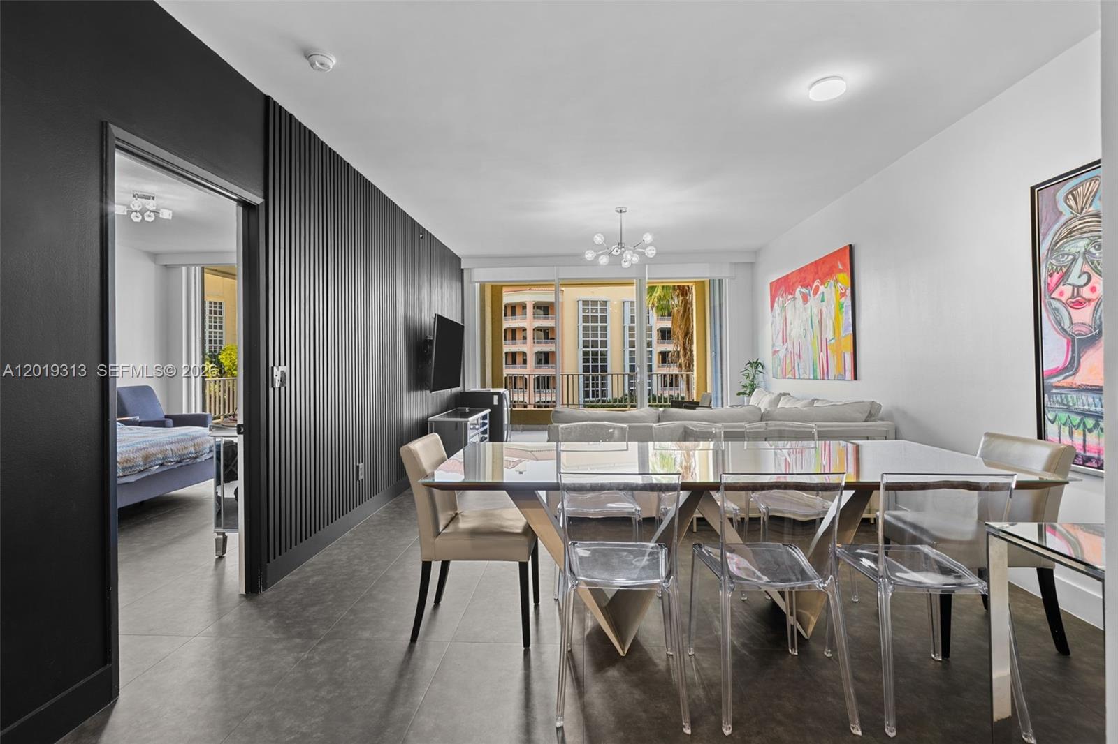 A dining area with a glass table and clear chairs sits before a living room — 713 Crandon Blvd # 404, Key Biscayne FL 33149, KEY BISCAYNE, FL