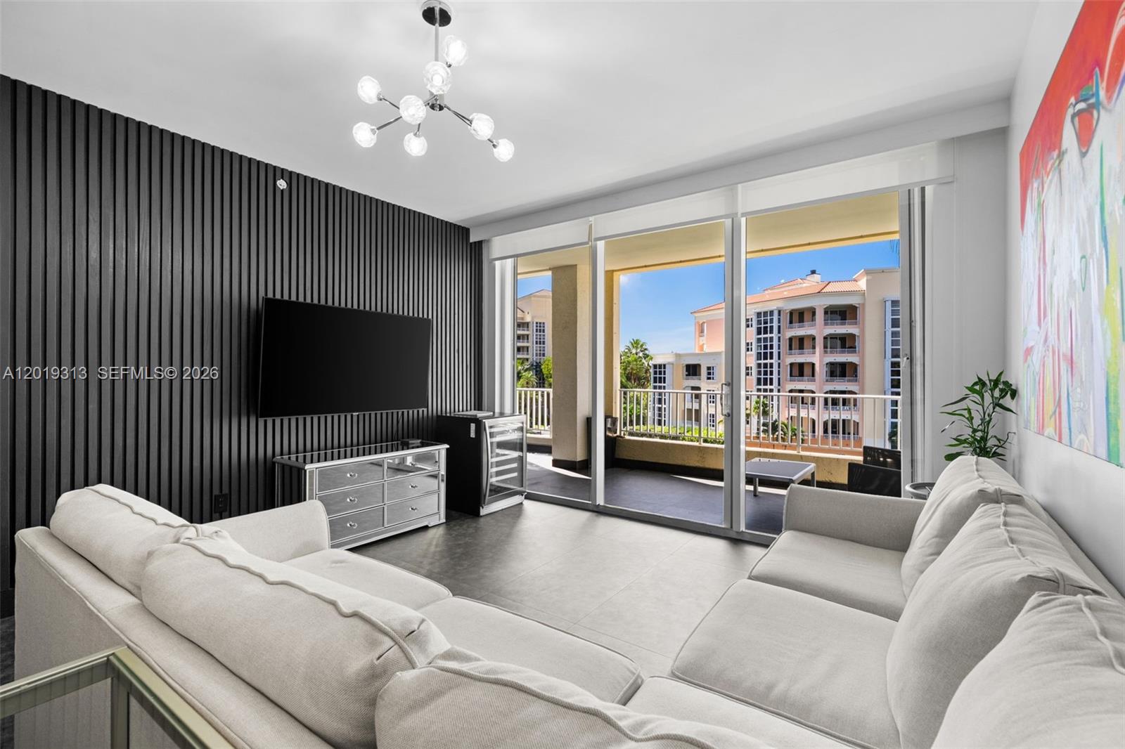A living room features a dark slatted accent wall, a mirrored console, and balcony access — 713 Crandon Blvd # 404, Key Biscayne FL 33149, KEY BISCAYNE, FL