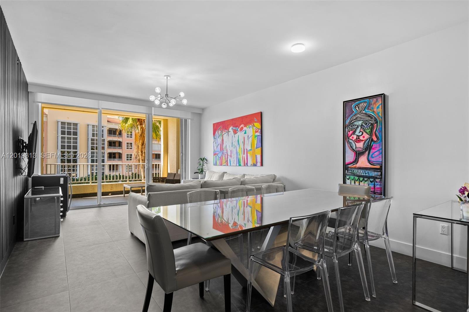 A modern living and dining area features a glass table, clear chairs, and vibrant wall art — 713 Crandon Blvd # 404, Key Biscayne FL 33149, KEY BISCAYNE, FL