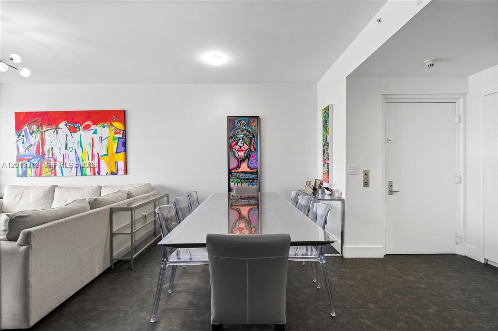 A dining room features a long glass table, clear chairs, and vibrant abstract wall art — 713 Crandon Blvd # 404, Key Biscayne FL 33149, KEY BISCAYNE, FL
