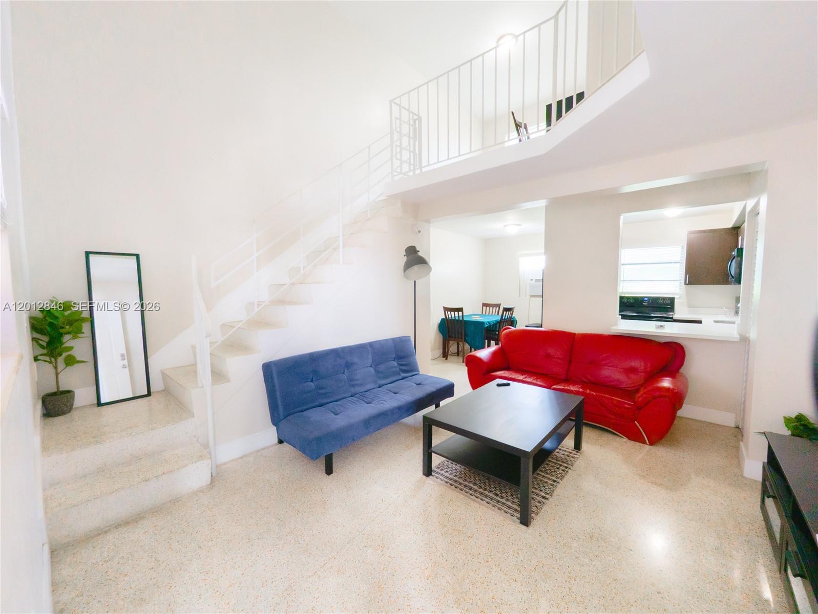 A living room features a red sofa, blue futon, coffee table, and stairs with railings — 1220 SW 5th St # 16, Miami FL 33135, MIAMI, FL