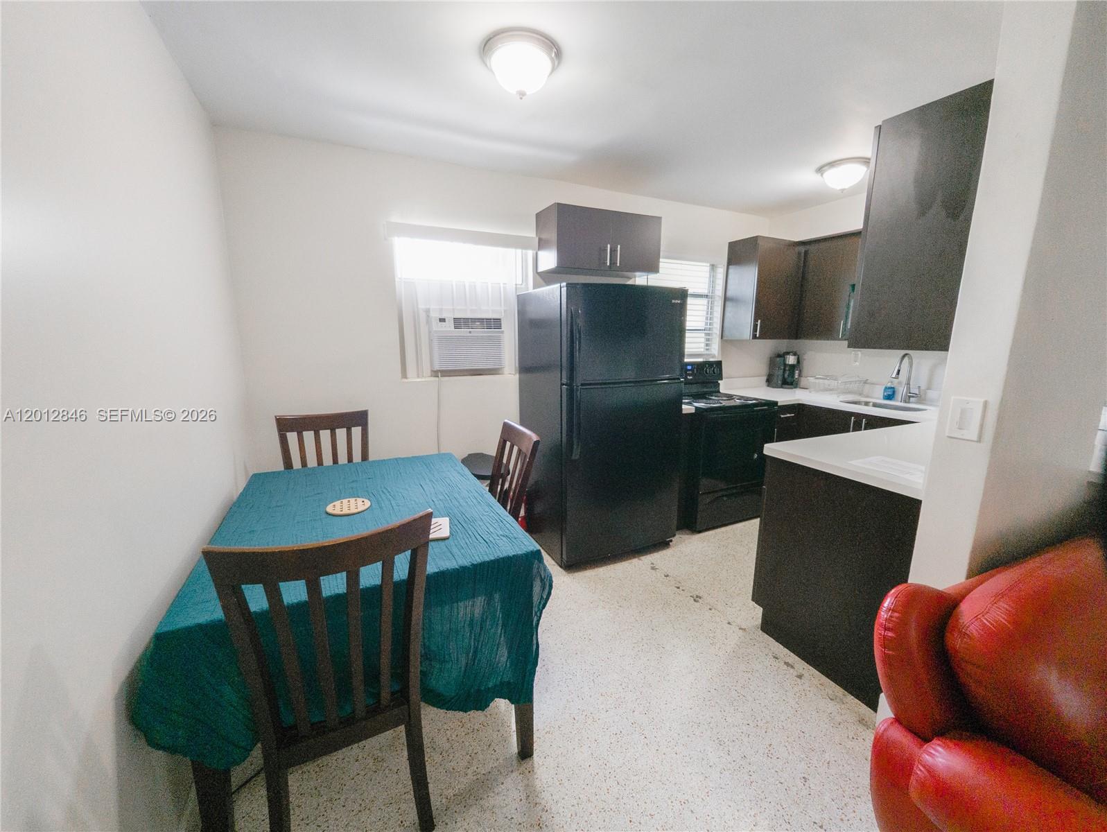 A kitchen and dining area features dark cabinets, black appliances, and a teal-covered table — 1220 SW 5th St # 16, Miami FL 33135, MIAMI, FL