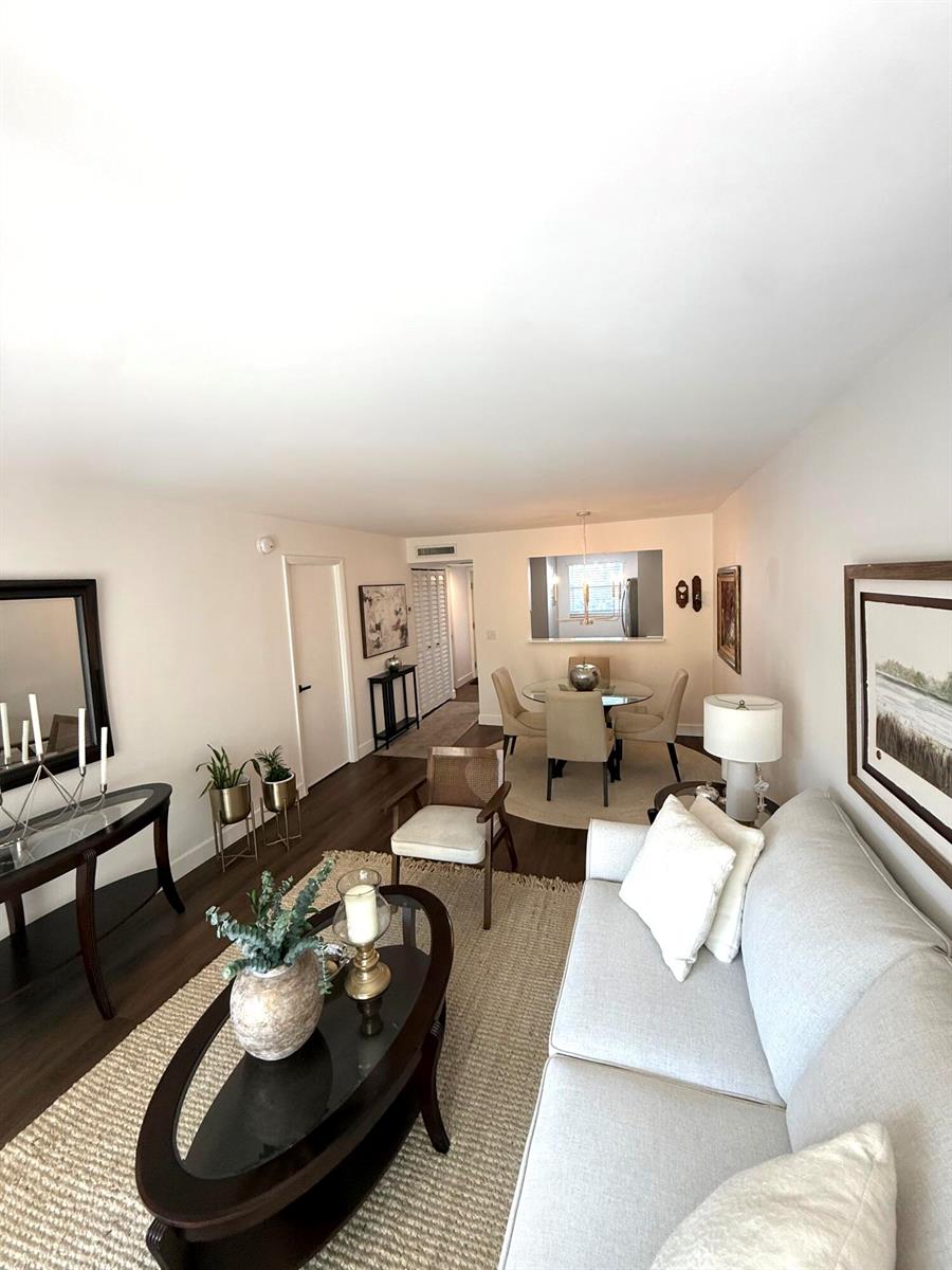 A living room and dining area feature light-colored furniture, a glass coffee table, and hardwood floors — 3170 Holiday Springs Boulevard # 304, Margate FL 33063, MARGATE, FL