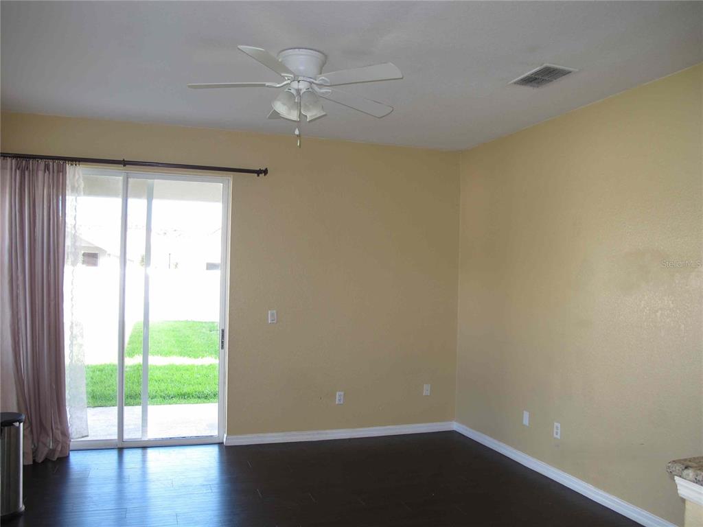 A room with dark wood flooring, beige walls, a ceiling fan, and a sliding glass door — 925 TORREY PINE DRIVE, WINTER SPRINGS, FL