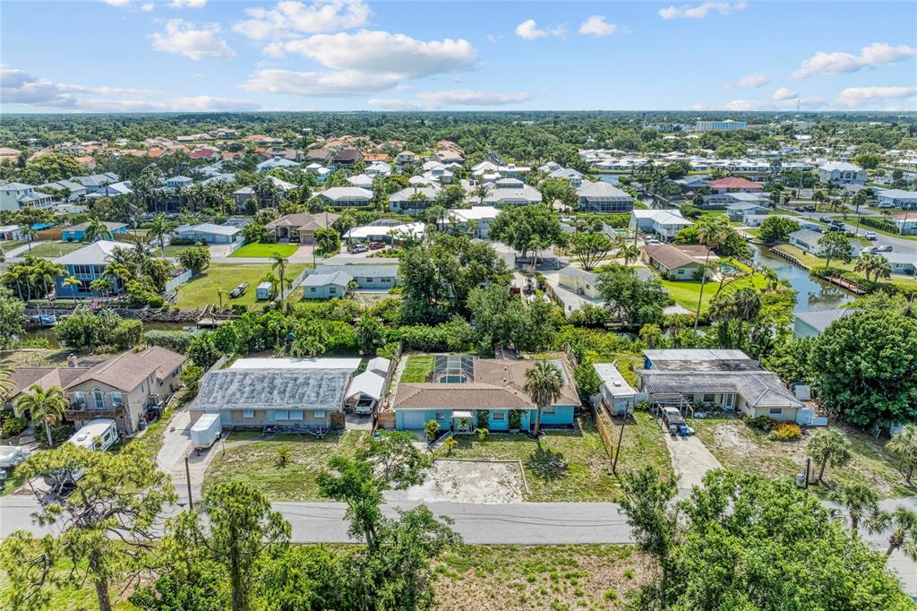 An aerial view shows three residential houses with yards and a canal in a neighborhood — 312 WINFIELD WAY, NOKOMIS, FL
