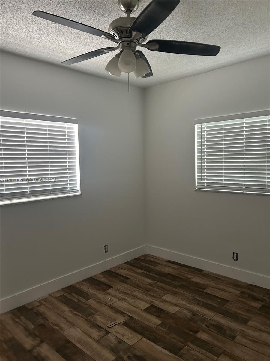 A bedroom features white walls, wood-look flooring, two windows with blinds, and a ceiling fan — 730 SW 4th St # A, Dania Beach FL 33004, DANIA BEACH, FL